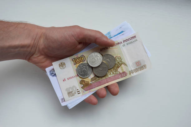 a pack of Russian rubles and coins on the open palm of a male hand on a white background. photo concept of paying for utilities, low incomes, pensions and salaries