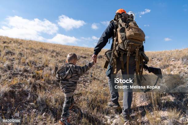 Vater Und Sohn Gehen Im Beifuß Spazieren Und Suchen Während Des Ersten Jagdausflugs Eines Kindes Nach Rehen Händchenhalten Stockfoto und mehr Bilder von Jagd