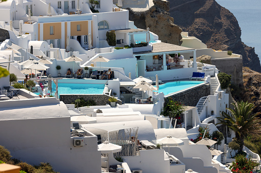 Oia, Santorini, Greece - July 3, 2021: Whitewashed houses with terraces and pools and a beautiful view in Oia on Santorini island, Greece