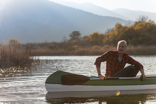 Two smiling couples on a joint trip with canoes on the autumn-colored Cerknica river. Dressed in casual clothes, they take selfies, laugh and enjoy the good mood on the water.