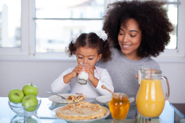 African-American young mother and daughter having breakfast stock photo