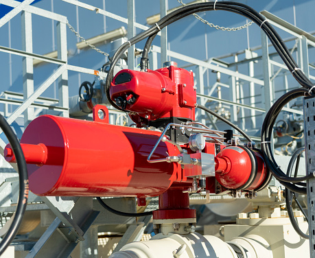 Emergency valve on gas equipment with a red actuator.