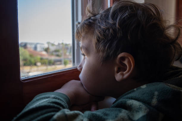 istock 4 Four year old boy looking out the window, emotional 1442017378