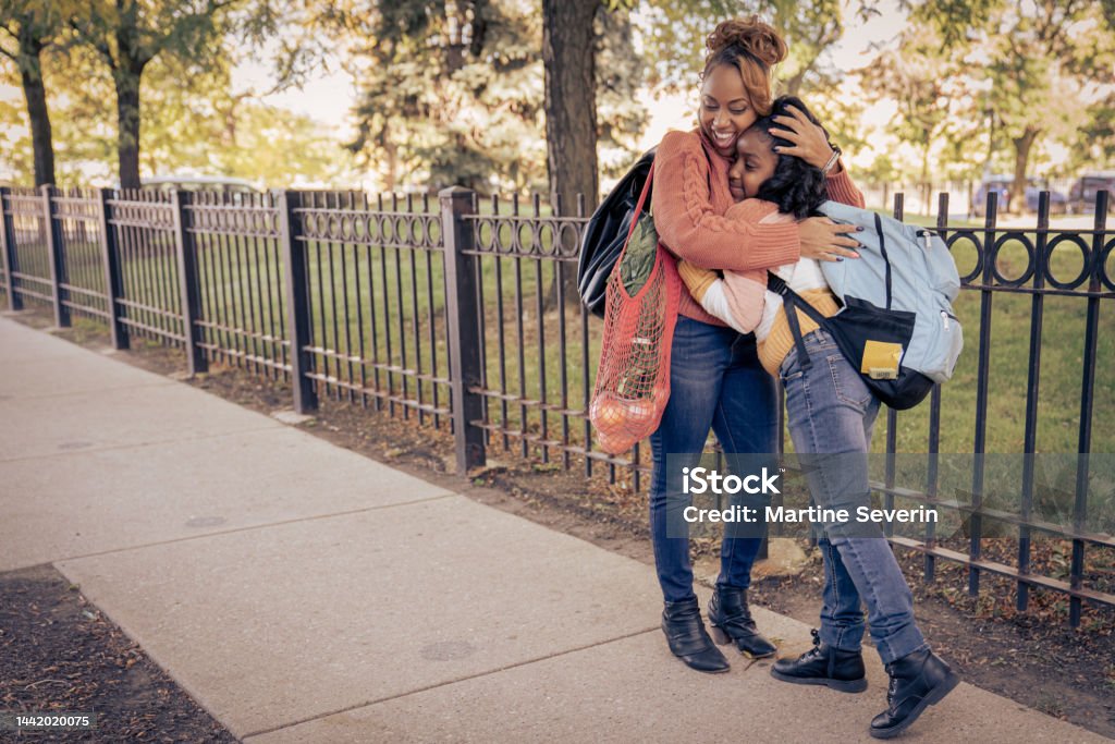 Visiting Community Fridge A mother picks her daughter up from school following a walk to a community refrigerator where they leave kale, apples, onions and veggies. 10-11 Years Stock Photo
