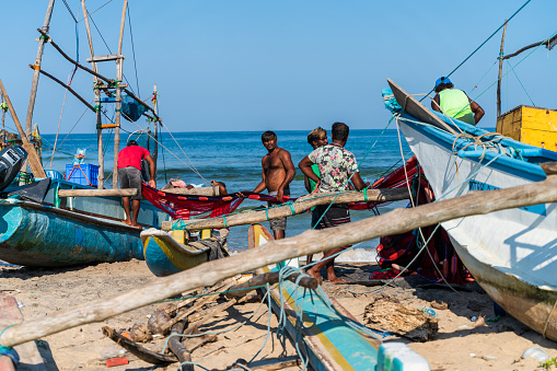 Galle, Sri Lanka - November 15, 2019: local fishermen are preparing nets on the beach, before sailing and fishing in the ocean.