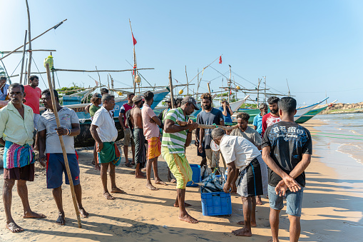 Locals buying fish on the beach from the local fishermen Mombassa Kenya Africa (350dpi)