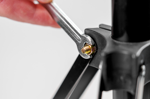 Wrench tightening a nut on a threaded bolt, fixing the photo tripod screw close-up