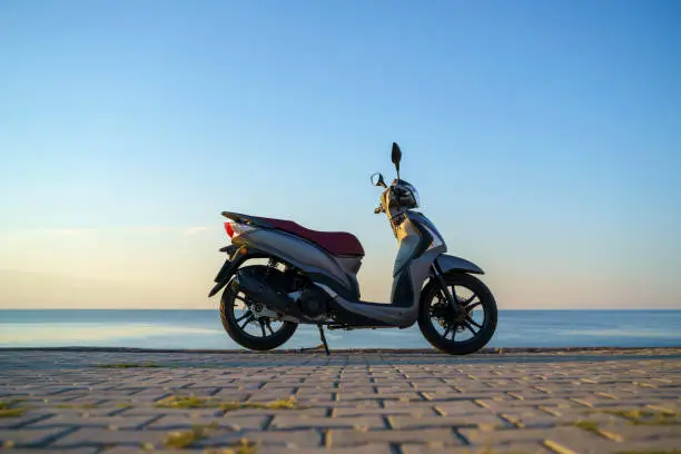 Moped Scooter parked by the sea in Konyaalti Beach, at sunset, Antalya, Turkey