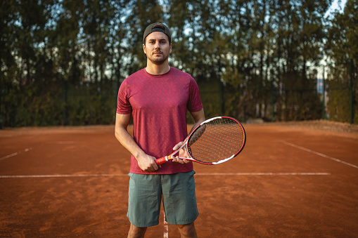 Portrait of male tennis player standing at the tennis court.