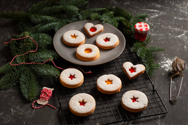 linzer kekse serviert auf einem mit fichtenzweigen verzierten teller - cookie heart shape shortbread christmas stock-fotos und bilder