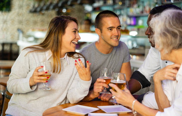 View on the young Latin couple talking to diversse group at a bar