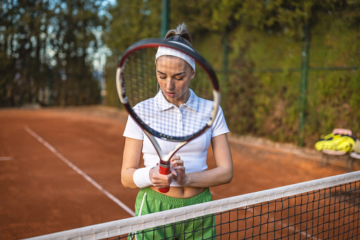 Portrait of female tennis player standing at the tennis court.