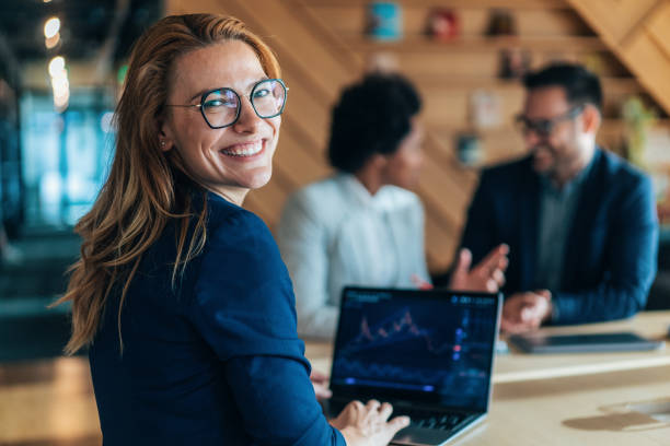 Portrait of crypto trader at the office Portrait of crypto trader at the office. Successful female trader in formalwear working in office, looking at camera in front of laptop screen, checking global currency index on fund exchange. Trading stock or cryptocurrencies. Trading app on screen. woman trading stocks stock pictures, royalty-free photos & images