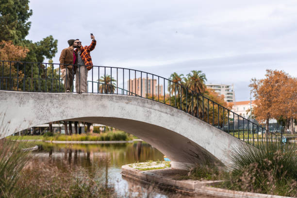 гей-пара делает селфи в парке - couple autumn embracing bridge стоковые фото и изображения