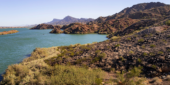 Tranquil southwestern desert wilderness landscape with red rock hill islands and blue water along the Colorado River near Havasu City, Arizona, USA