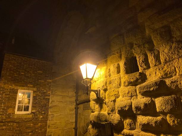 istock Old fashioned street light at night on an ancient town building wall 1442036155