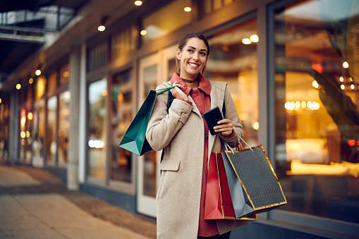 Young woman carrying shopping bags and feeling satisfied after spending a day at the mall.