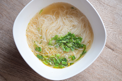Rice vermicelli noodles bowl - rice noodles soup bowl with coriander on wooden background