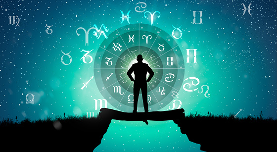 Astrological zodiac signs inside of horoscope circle. Man silhouette consulting the stars and moon over the zodiac wheel and milky way background. The power of the universe concept.
