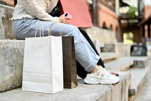 cropped image, Two female friends sitting on the street stairs with their shopping bags. shopping concept