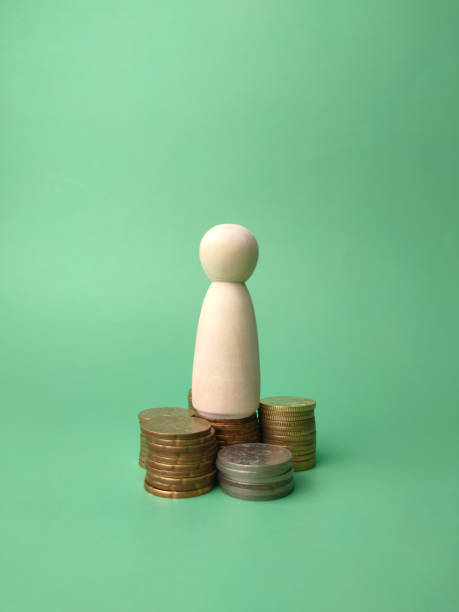 istock Wooden people figures and coins on a green background. 1442072293