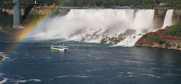 Canadian and Bridal Veil Falls including Maid of the Mist boat sailing on Niagara River with rainbow multicolor colors, Canada and USA natural border