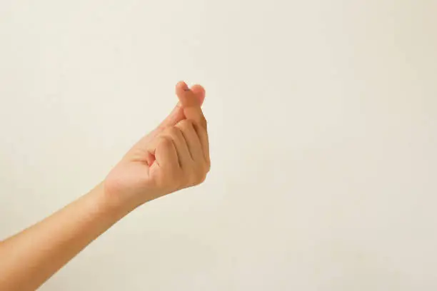 Photo of Female hand with finger depicting Korean symbol of love isolated on white background.