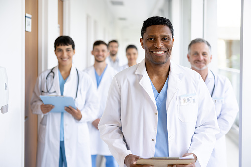 Portrait of a happy attending physitian guiding a group of resident doctors at the hospital and looking at the camera smiling