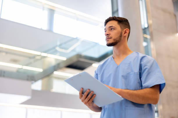 fotografii de stoc, fotografii și imagini scutite de redevențe cu asistentă medicală care lucrează la spital și deține o fișă medicală - asistentă medicală de sex masculin