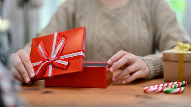istock A woman open a beautiful Christmas gift box at her table. cropped image 1442080521
