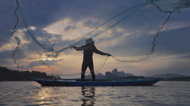 Fisherman throwing fishing nets during sunset on boats at the lake