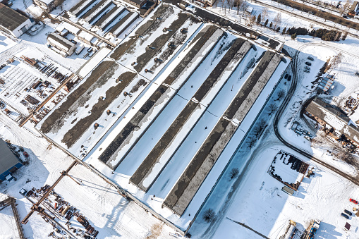 industrial area with snow-covered manufacturing buildings, warehouses, industrial equipment. aerial view at winter time.