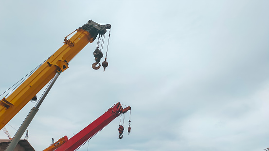 Jakarta, Indonesia - June 8, 2022: Beautiful red and yellow top boom of telescopic mobile crane with clear sky with cloud.