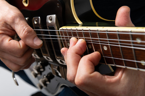 Close-up of a guitarist's fingers and a fragment of a vintage electric guitar