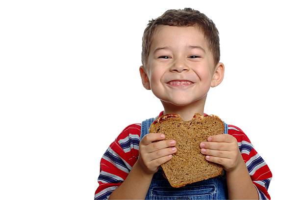 Boy with Peanut Butter and Jelly Sandwich on Whole Wheat A 5-year-old boy enjoying a peanut butter and jelly sandwich on whole wheat bread ian stock pictures, royalty-free photos & images
