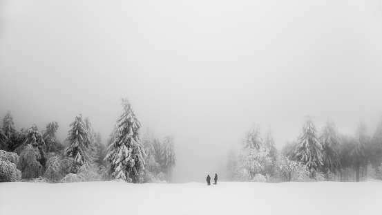 A mysterious view of a snow-covered meadow with two people near the Grosser Feldberg mountain, Germany