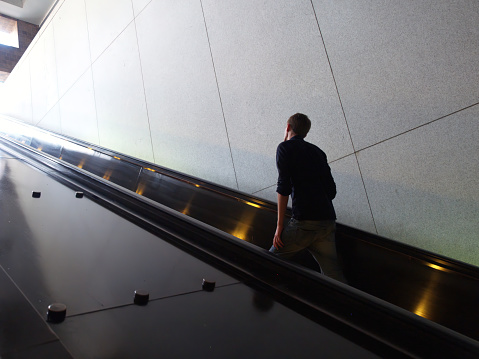 A young man rides the escalator up.