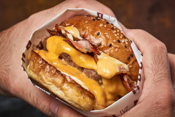 istock Male's hands holding a delicious double cheeseburger 1442103592