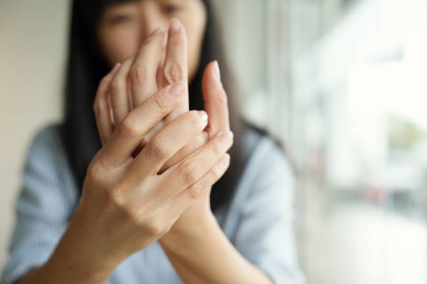 Close-up woman massaging her arthritic hand and wrist, she is suffering from pain and rheumatism. stock photo
