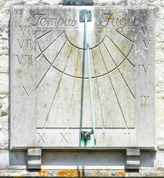 Old stone sundial on wall Old stone sundial fixed to facade of building. ancient sundial stock pictures, royalty-free photos & images