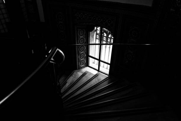 A grayscale shot of a staircase near a window