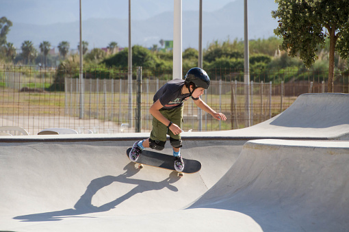 A teenage Hispanic boy skateboarding in a skateboard park