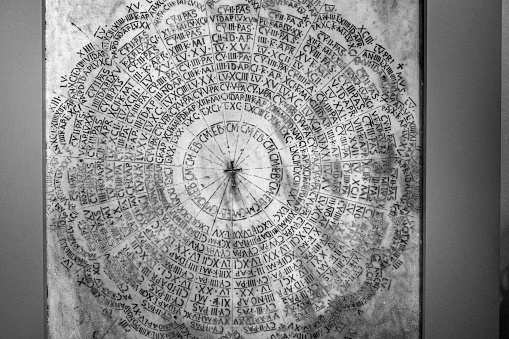A closeup of a Latin liturgical calendar on a marble grave in Ravenna, Italy