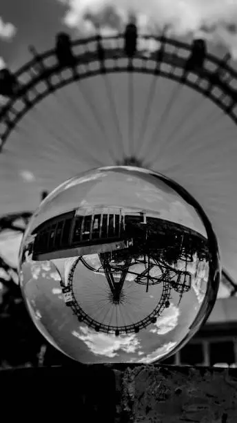 A greyscale shot of a Ferris wheel reflected on a small iceball