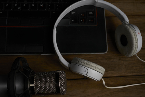 A top view of headphones and a microphone on the black laptop