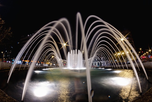 A long exposure of a water fountain captured with its lights on at night