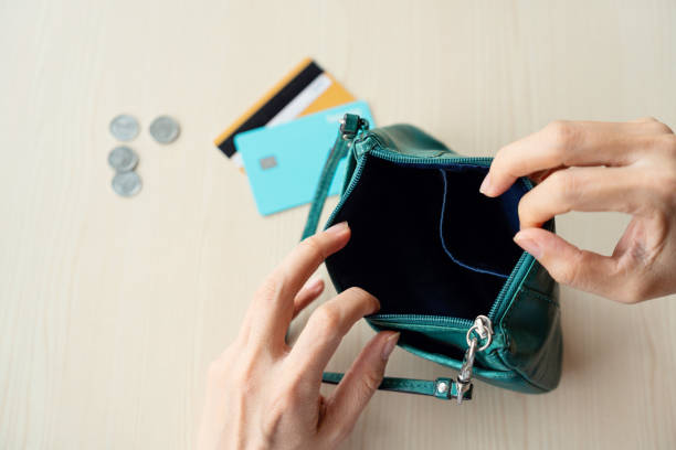 istock Midsection Of Woman Showing Empty Purse Over Table 1442110943