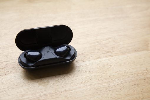 A top view of wireless earbuds on a wooden surface - copy space
