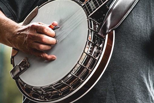 A closeup of man's hands playing banjo.