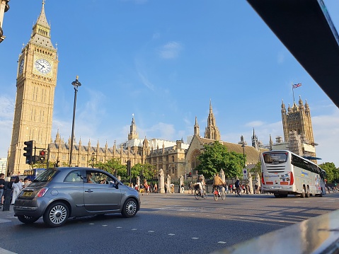 London, United Kingdom – October 21, 2022: A London street view full of traffic and people, with Westminster Abby and Big Ben in the background, on a sunny day in summer